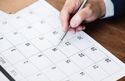 Core to any IR plan is a calendar with at least one roadshow a quarter. Image is of a man's hand holding a pen pointing to a date on a calendar.