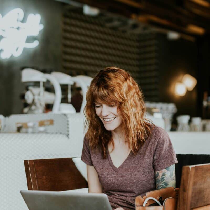 A woman is smiling while using a laptop computer