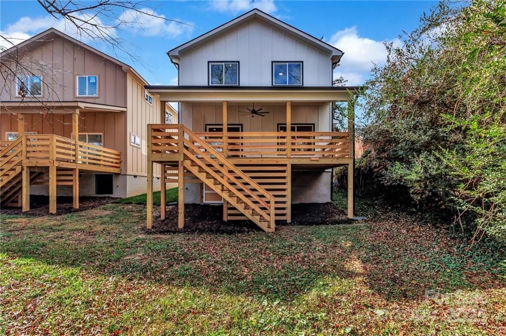 Two-story houses with wooden decks and staircases set in a grassy yard, partially obscured by bushes.