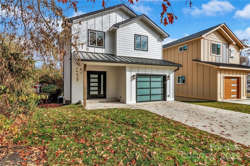 Two-story modern homes with white and beige siding, concrete driveways, and garages on a sunny day.
