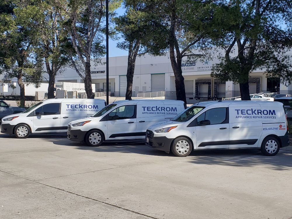 Three white vans are parked on the side of the road.