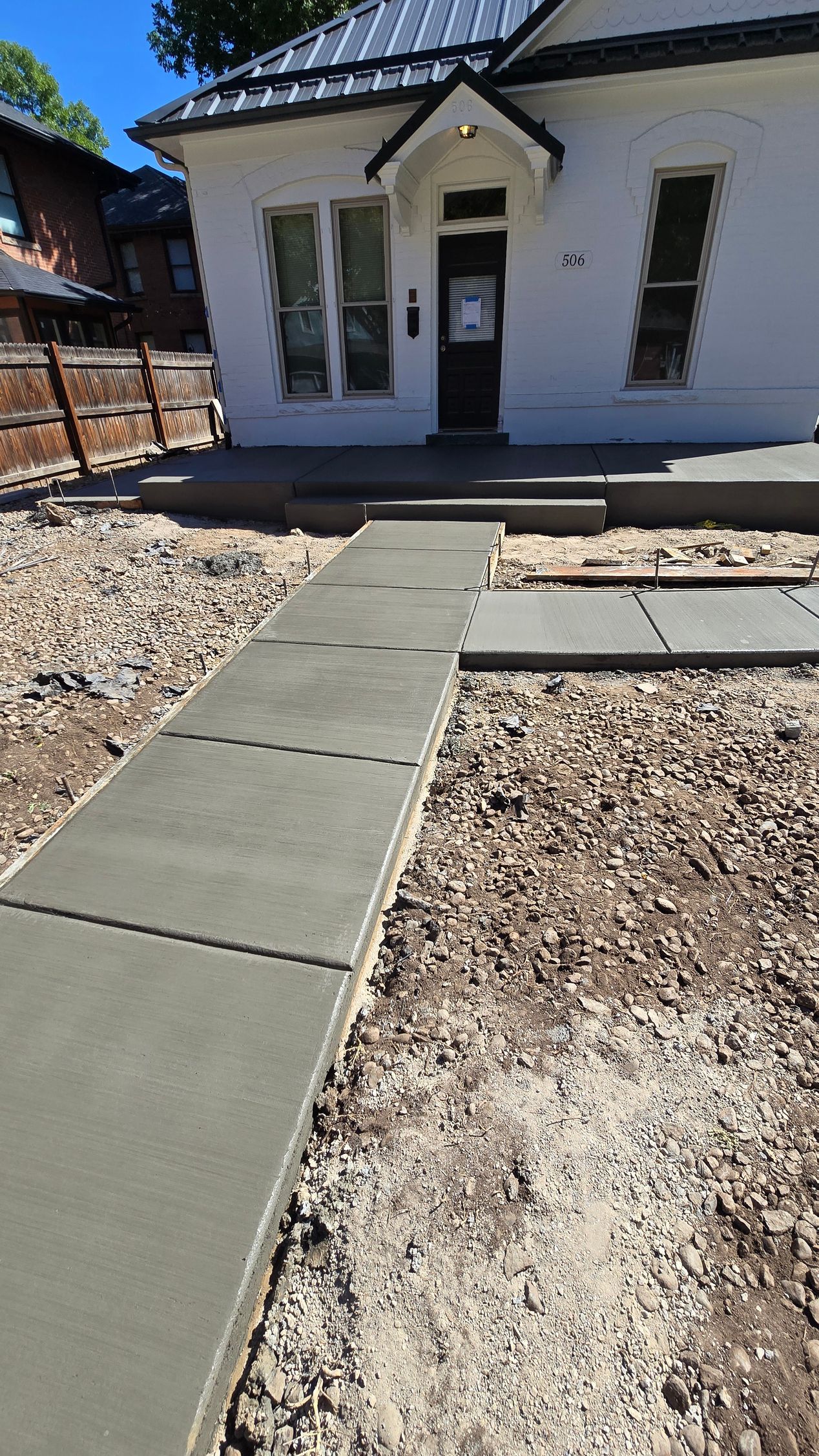 A concrete walkway leading to a row of houses with a white fence.