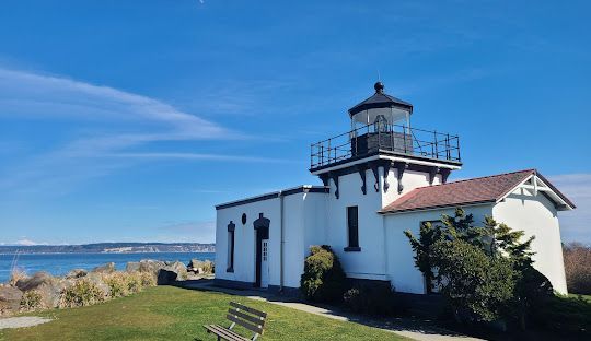 A lighthouse is sitting on top of a grassy hill overlooking the ocean.