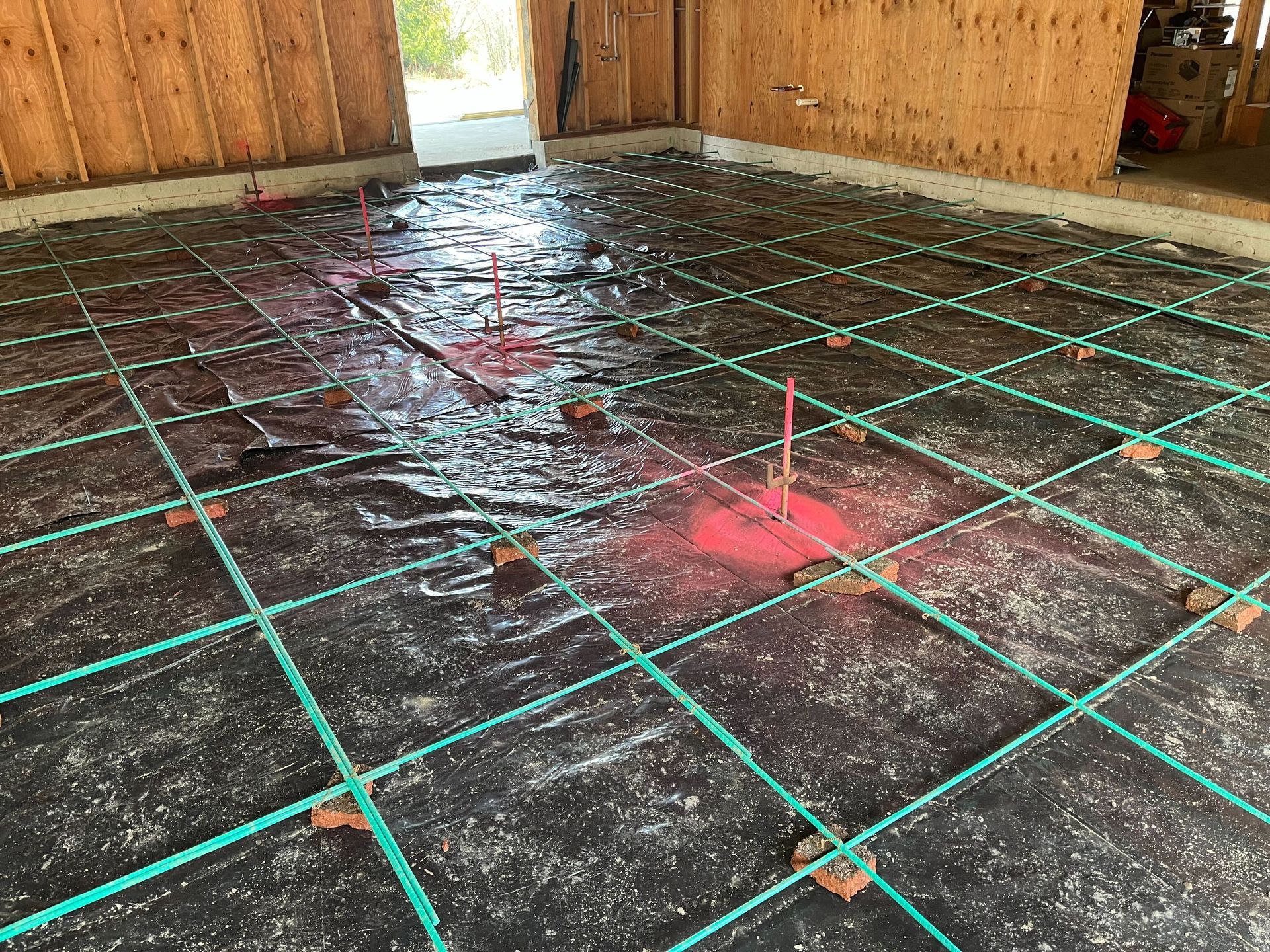 A concrete floor with green lines and a red marker on it.