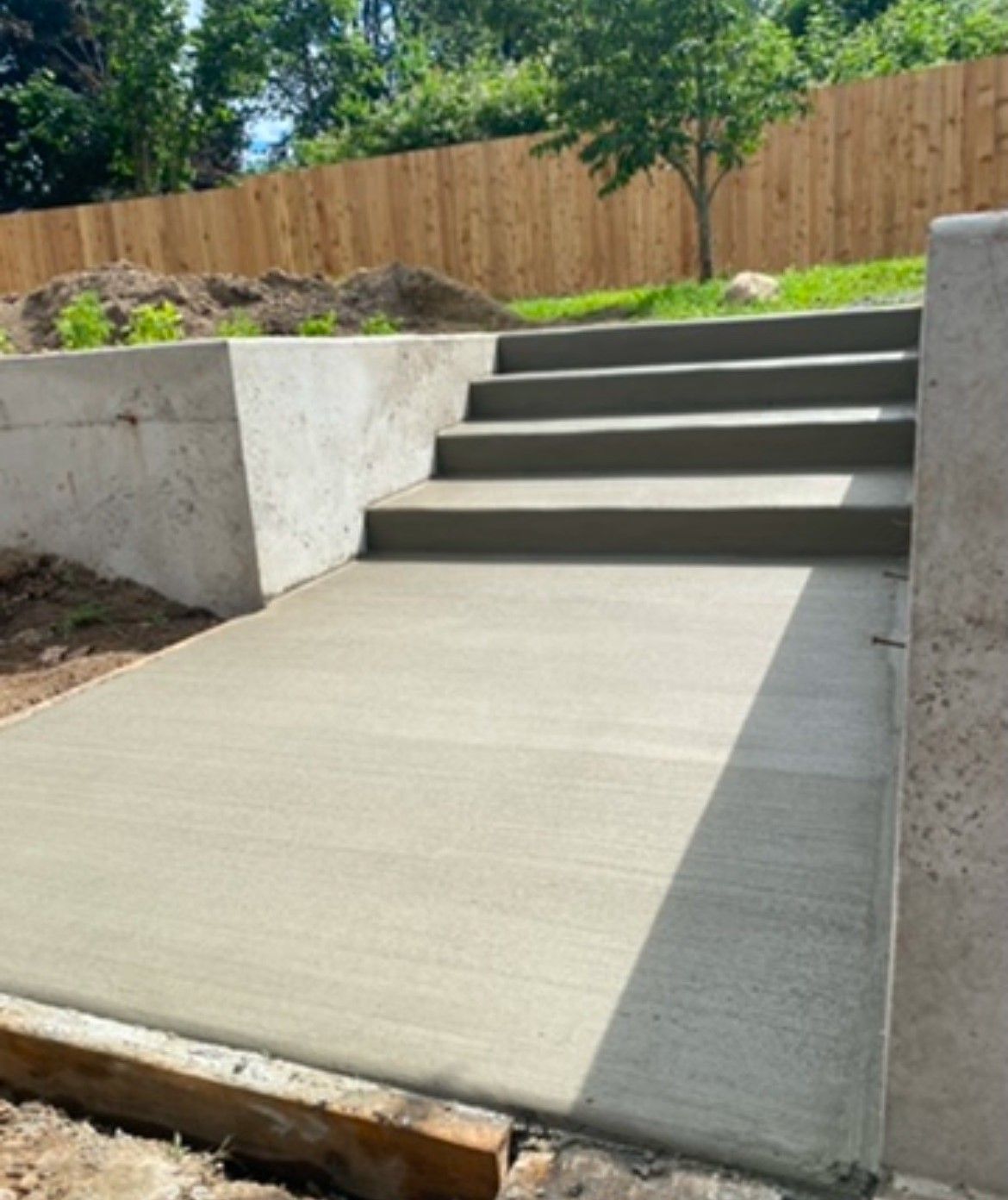 A concrete walkway with stairs leading up to a wooden fence.