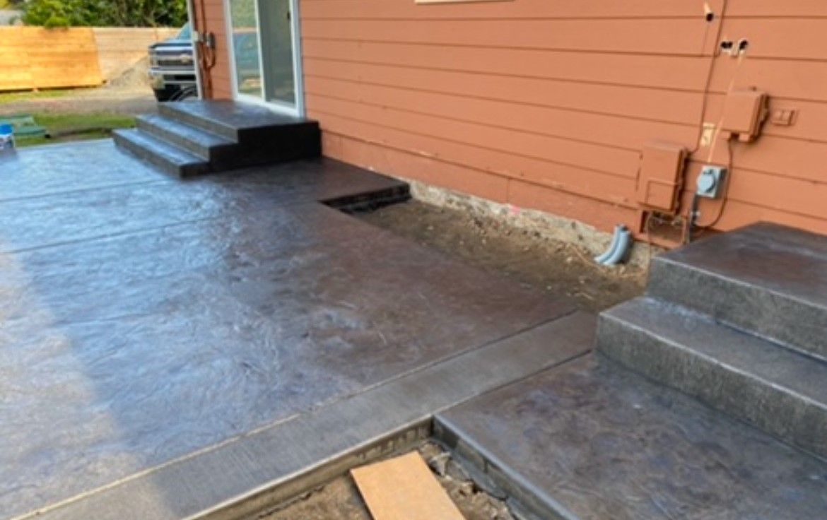 A concrete patio with stairs leading up to a house.