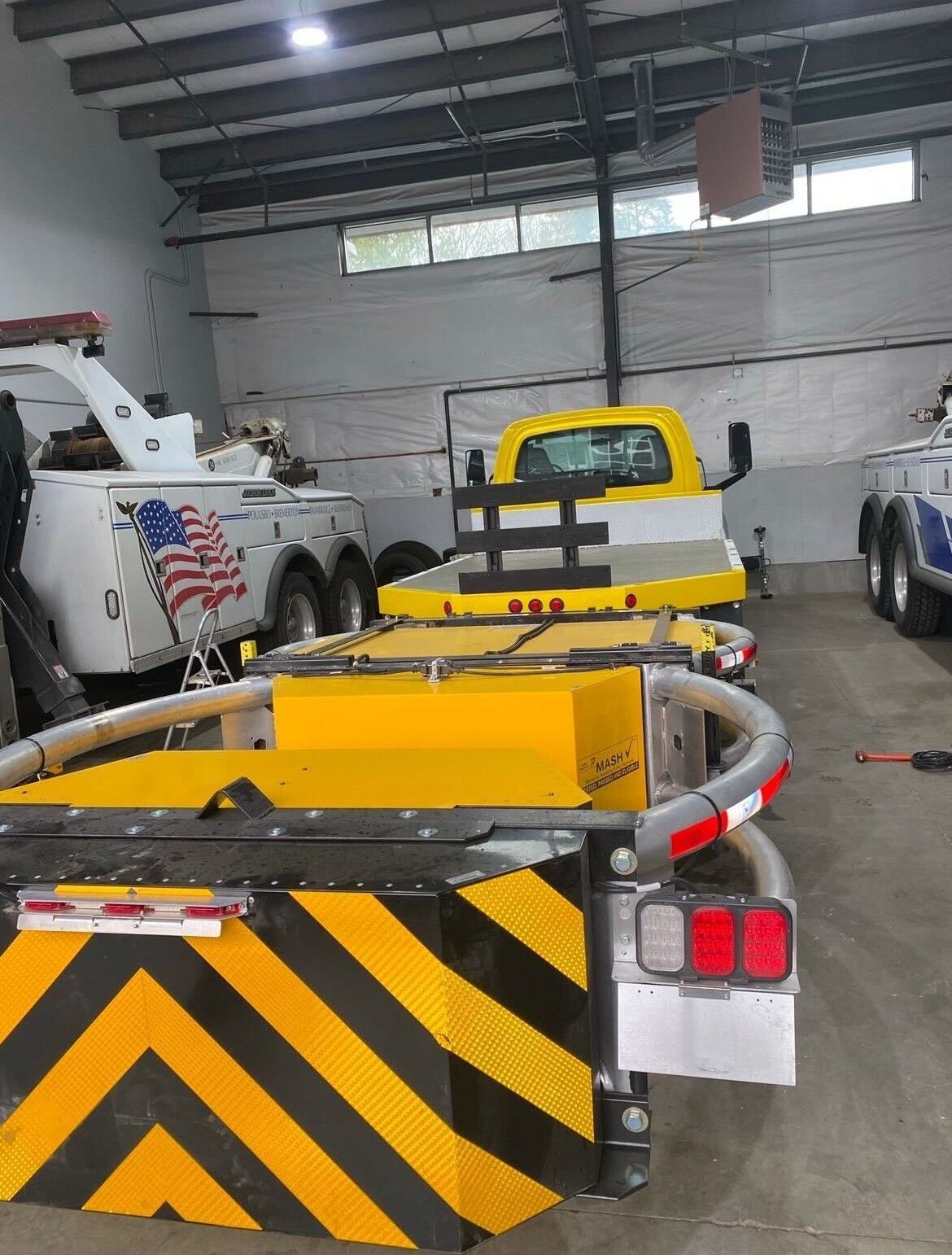 A row of tow trucks are parked in a garage