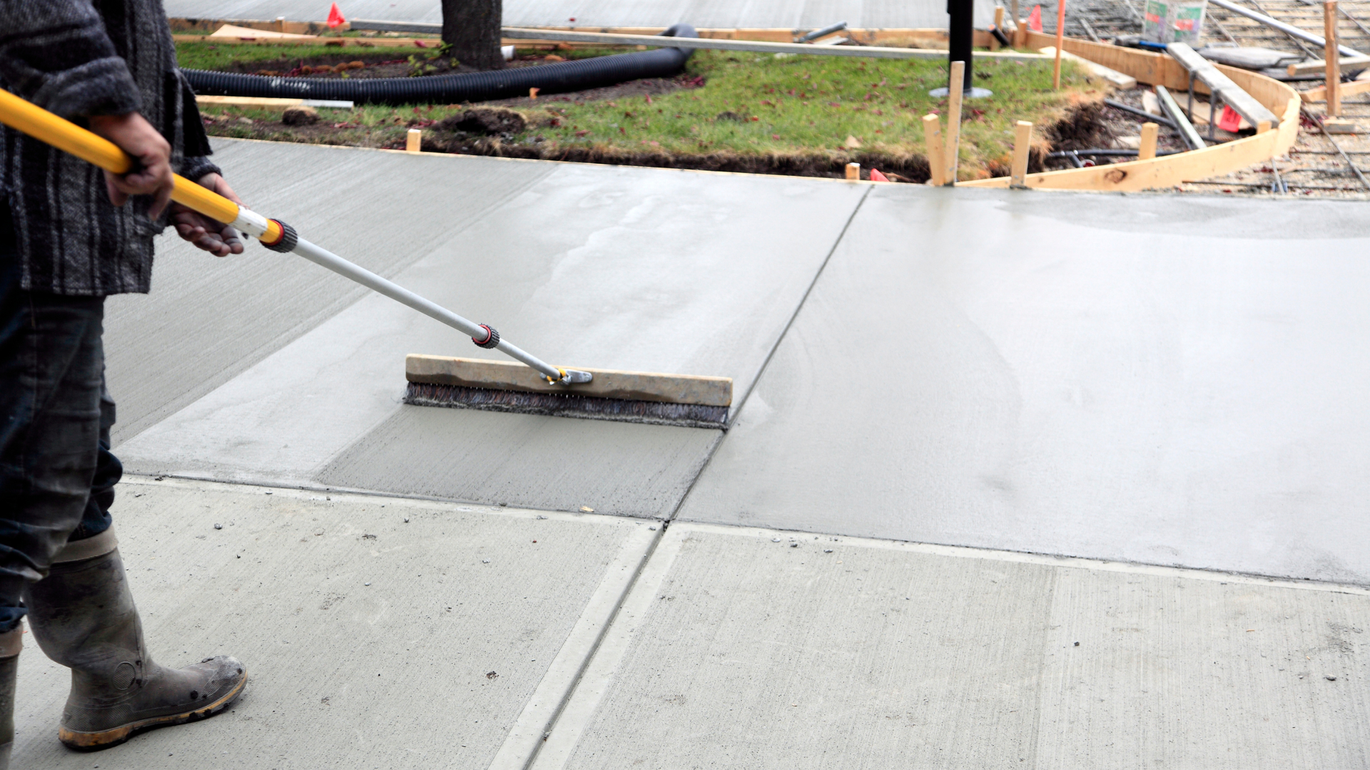 Homeowner inspecting small cracks and control joints on a concrete driveway in Silverdale WA