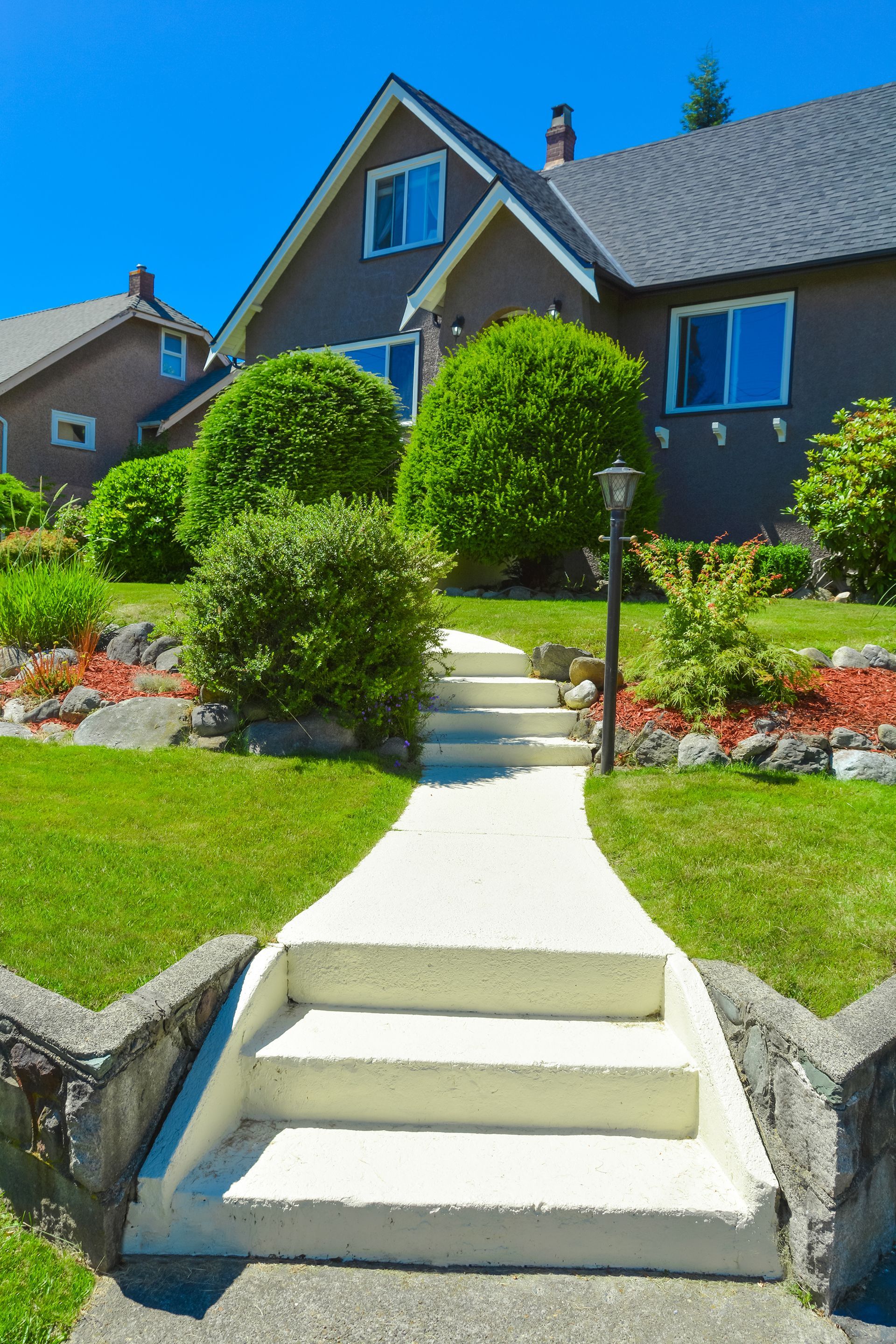 A concrete walkway leading to a house with stairs leading up to it.