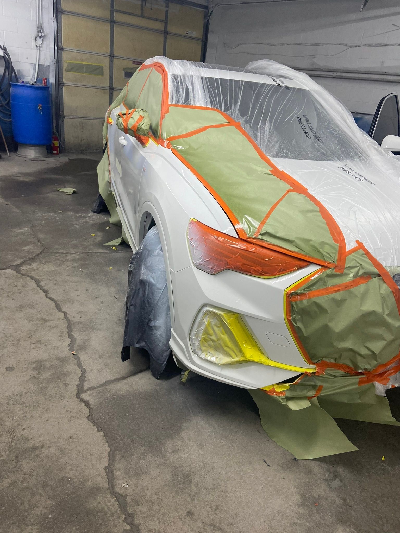 A White Car Is Being Painted in A Garage — Chicago, IL — Ecuamex Autobody Inc.