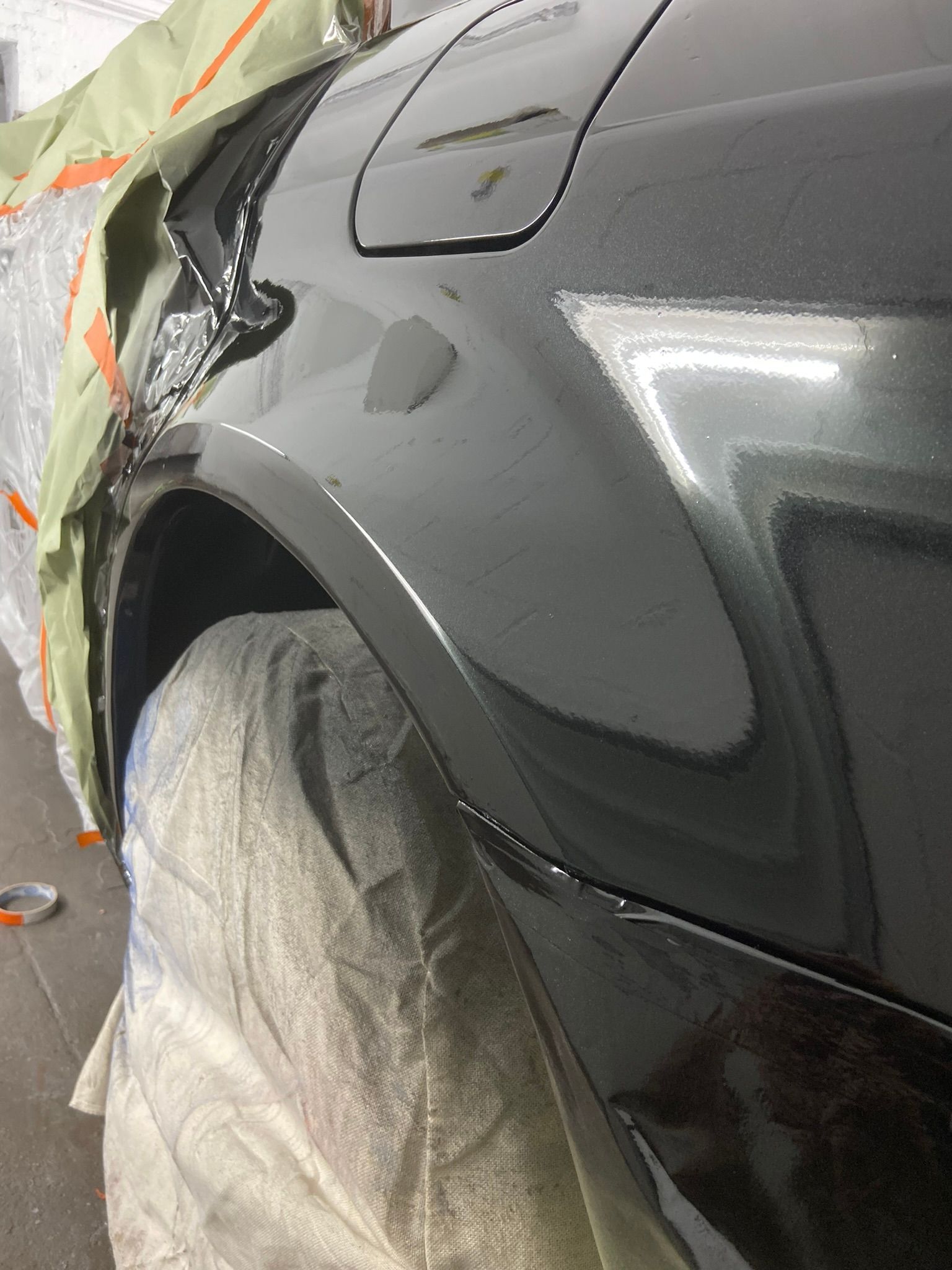 A Black Car Is Being Painted in A Garage — Chicago, IL — Ecuamex Autobody Inc.