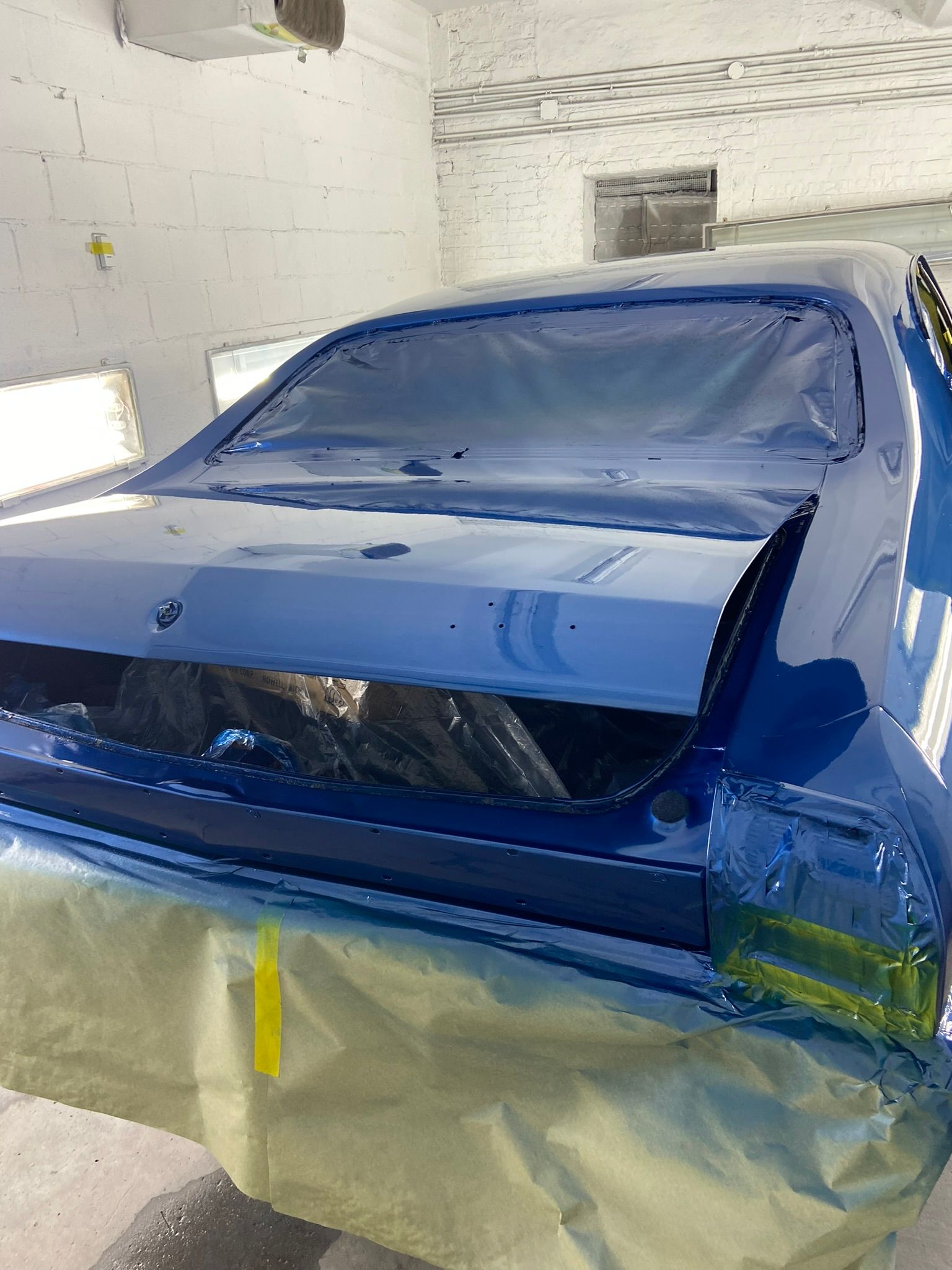 A Blue Car Is Being Painted in A Garage — Chicago, IL — Ecuamex Autobody Inc.