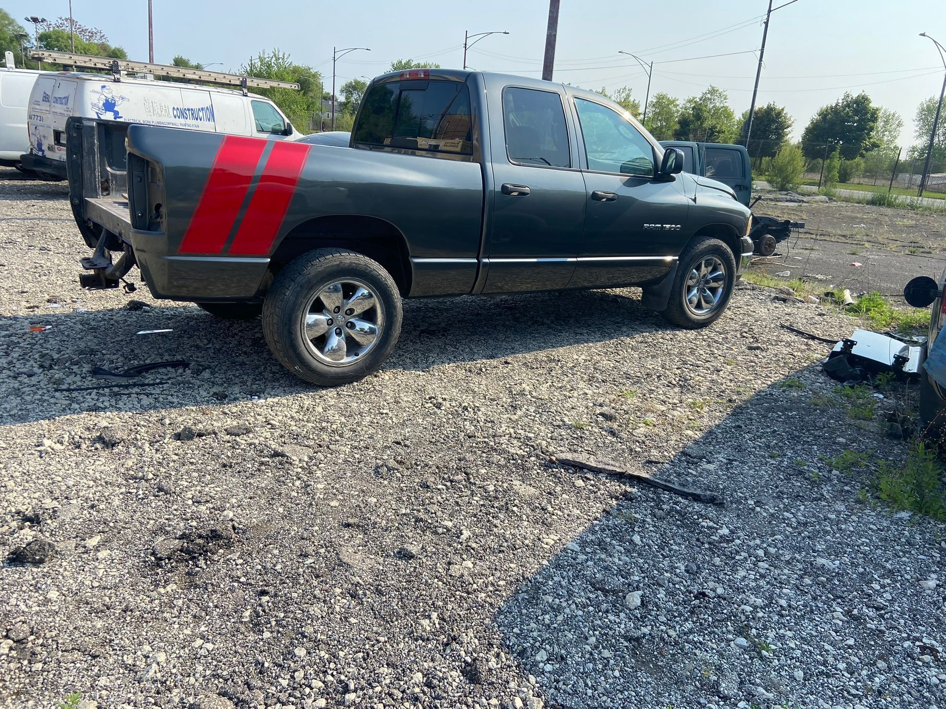 A Black Truck with Red Stripes on The Bed Is Parked in A Gravel Lot — Chicago, IL — Ecuamex Autobody Inc.
