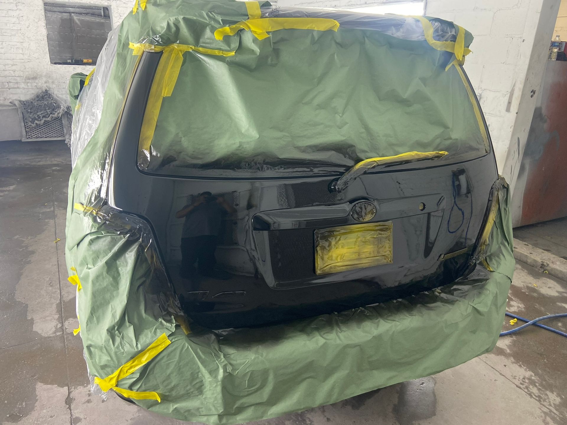 A Black Car Is Covered in A Green Tarp and Yellow Tape — Chicago, IL — Ecuamex Autobody Inc.