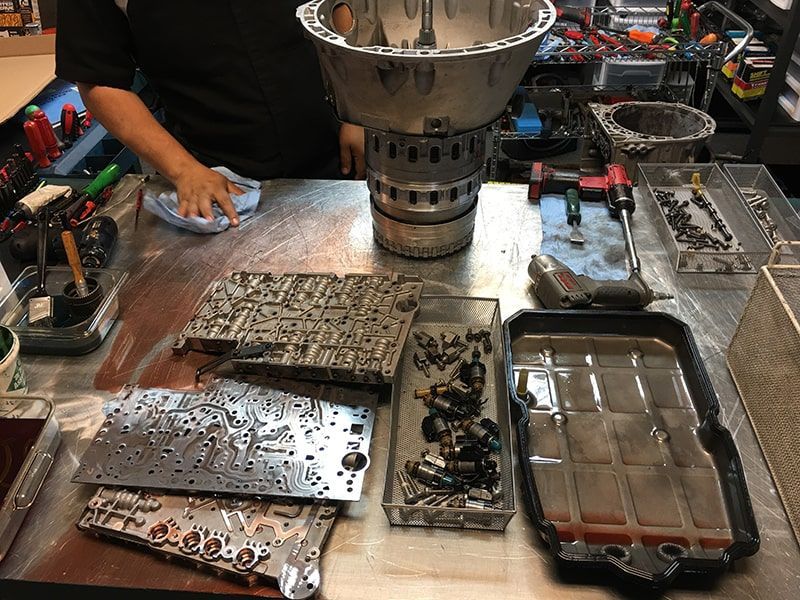 A man is standing at a table with a lot of tools on it. | Aus Tex Transmissions