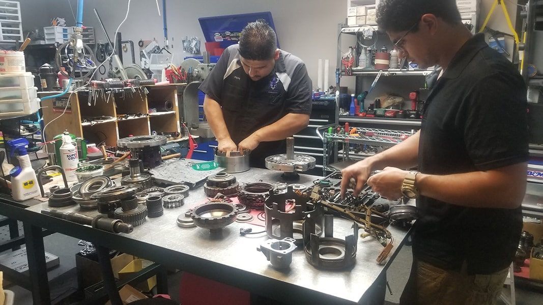 Two men are working on a machine in a garage. | Aus Tex Transmissions