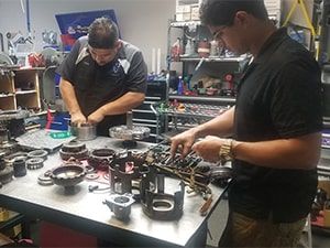 Two men are working on a machine in a garage. | Aus Tex Transmissions