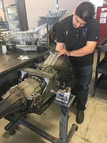 A man is working on a gearbox in a garage. | Aus Tex Transmissions
