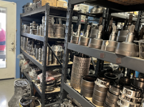 Shelves filled with various metal parts in a warehouse setting, likely for machinery or automotive repair. | Aus Tex Transmission