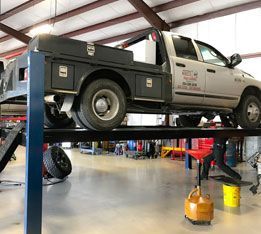 A truck is sitting on top of a lift in a garage. | Aus Tex Transmissions