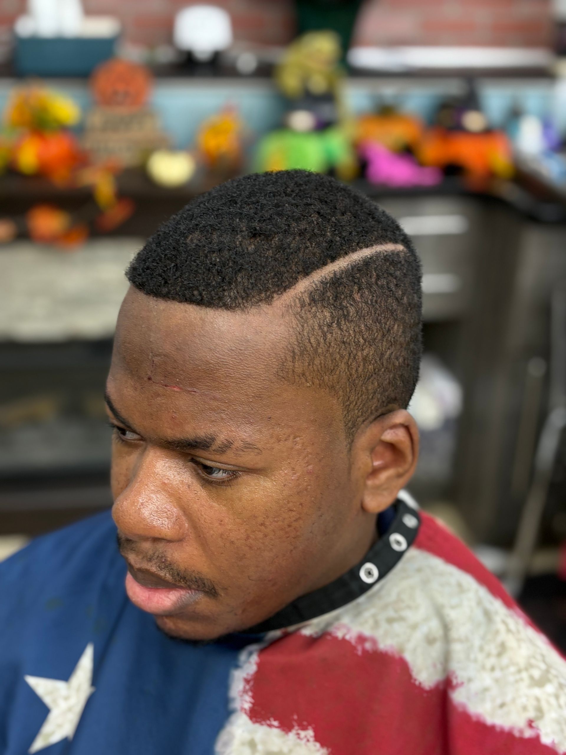 Man having hair washed in a salon sink. Barber holding a showerhead over his head.