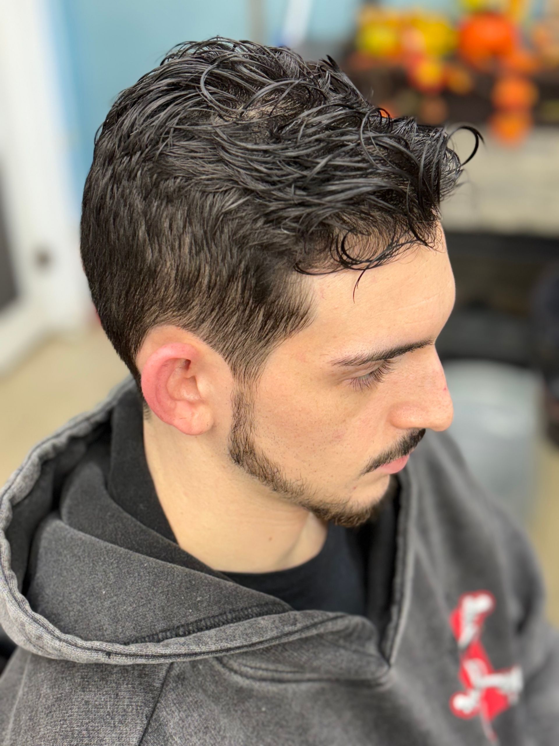 Barber trimming a man's graying beard with clippers; close-up view.