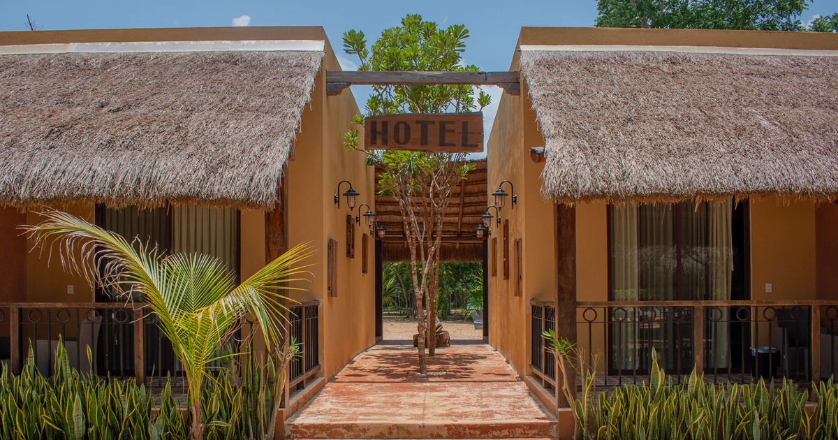 Un hotel con techo de paja está rodeado de palmeras.