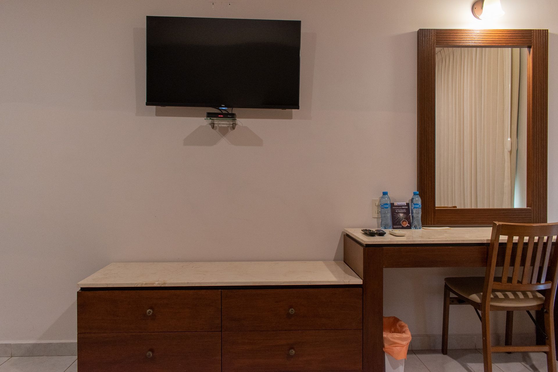 Una habitación de hotel con escritorio, silla, televisión y espejo.