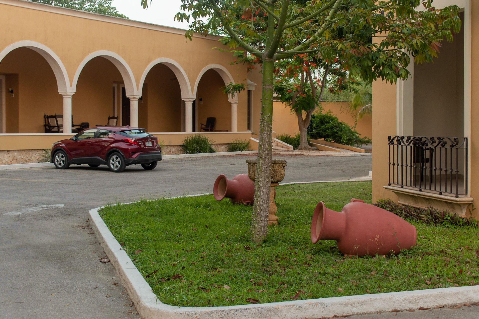 Un coche rojo está aparcado delante de un hotel.