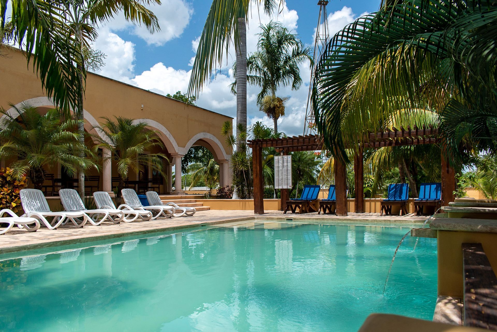 Una gran piscina rodeada de sillas y palmeras.