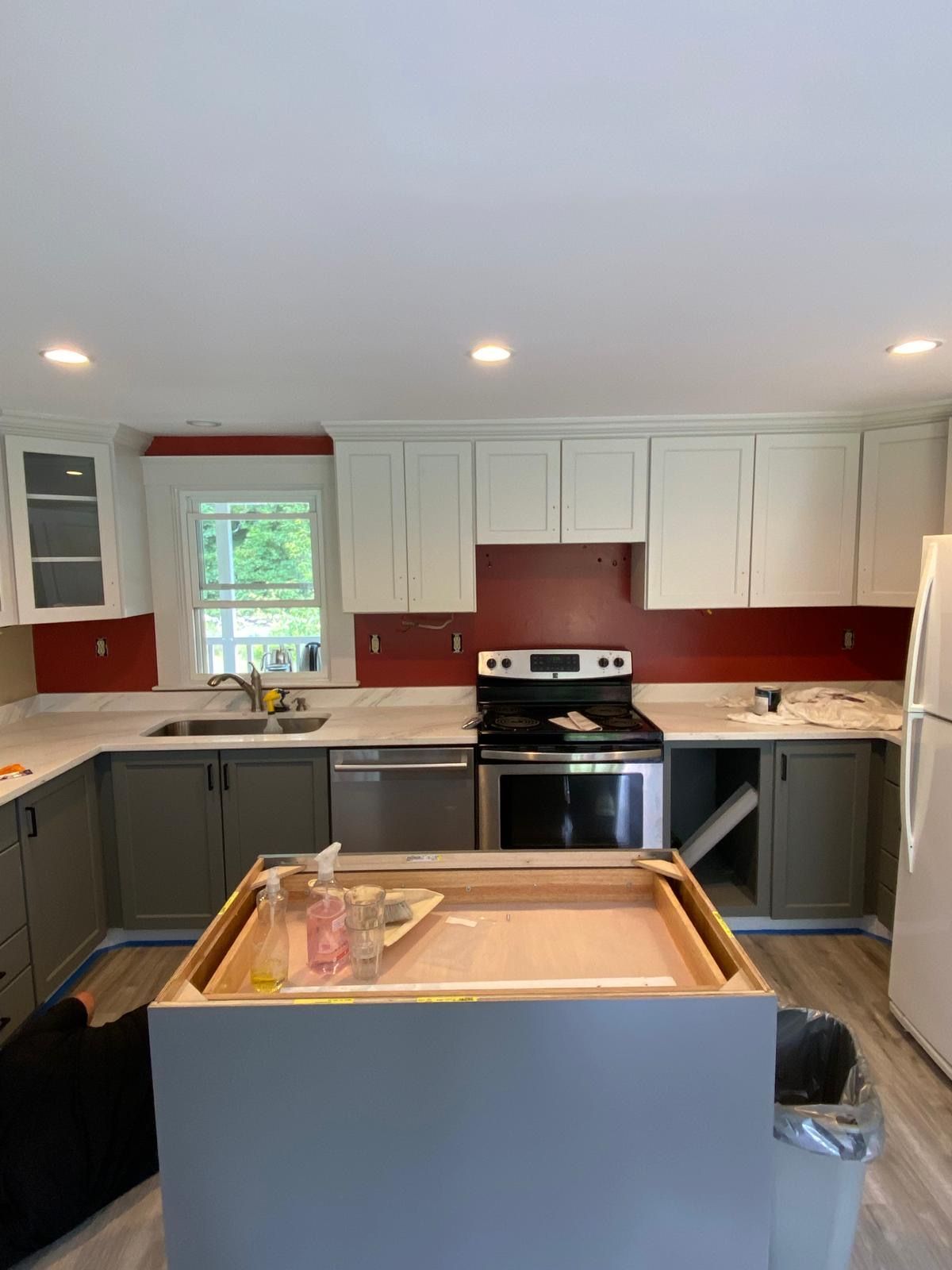Kitchen renovation: white and gray cabinets, red backsplash, island, stainless steel appliances, window. Kitchen renovation: white and gray cabinets, red backsplash, island, stainless steel appliances, window.