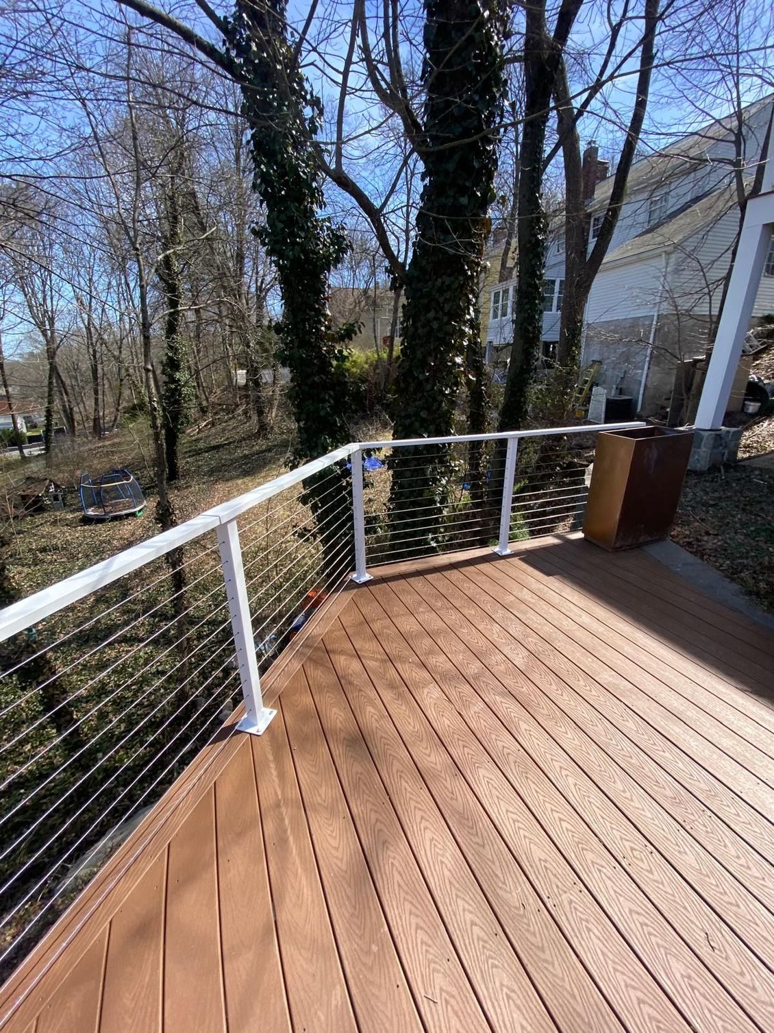 Deck with brown boards and cable railing overlooking trees. Deck with brown boards and cable railing overlooking trees.