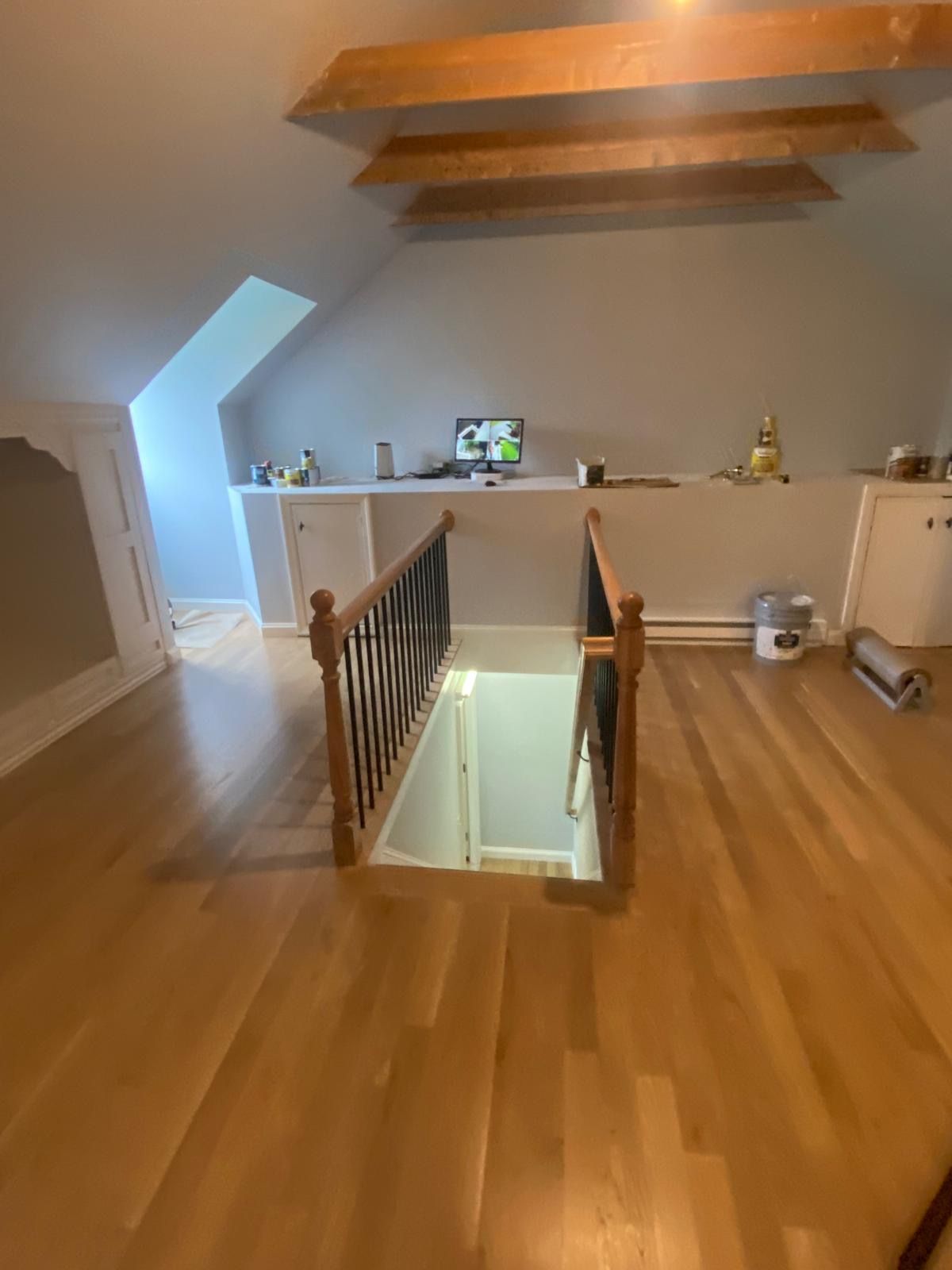 Wooden floor, stairs leading down, built-in shelves, sloped ceiling with beams, attic space. Wooden floor, stairs leading down, built-in shelves, sloped ceiling with beams, attic space.