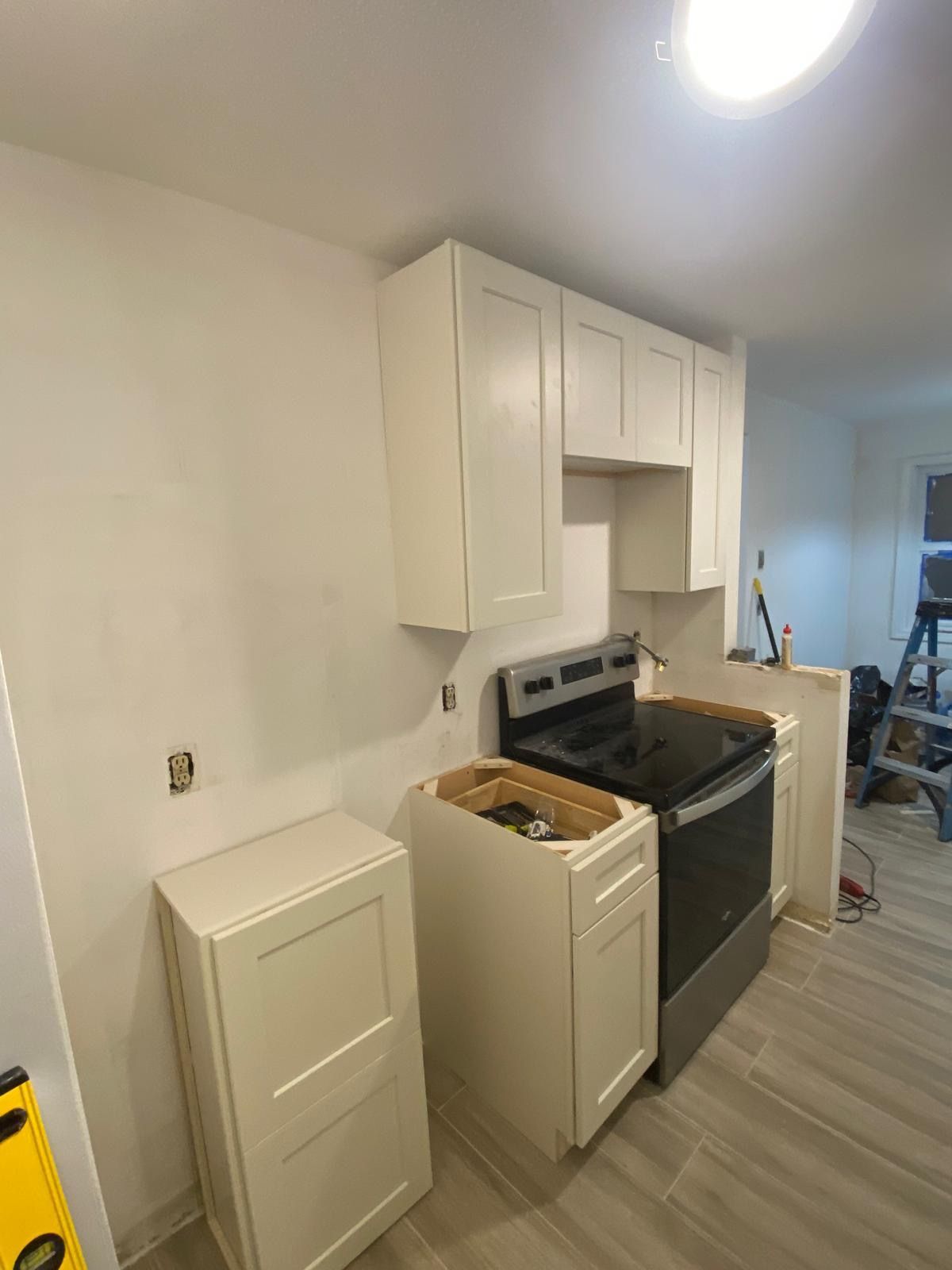 Kitchen under construction with white cabinets, stove, and unfinished walls. Kitchen under construction with white cabinets, stove, and unfinished walls.