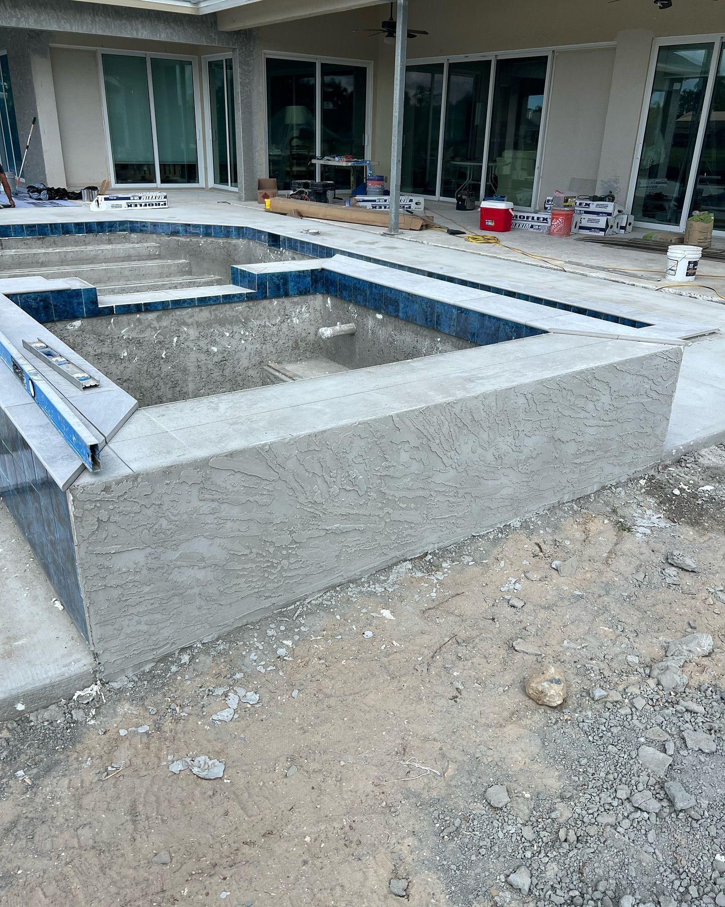 A swimming pool is being built in the backyard of a house.
