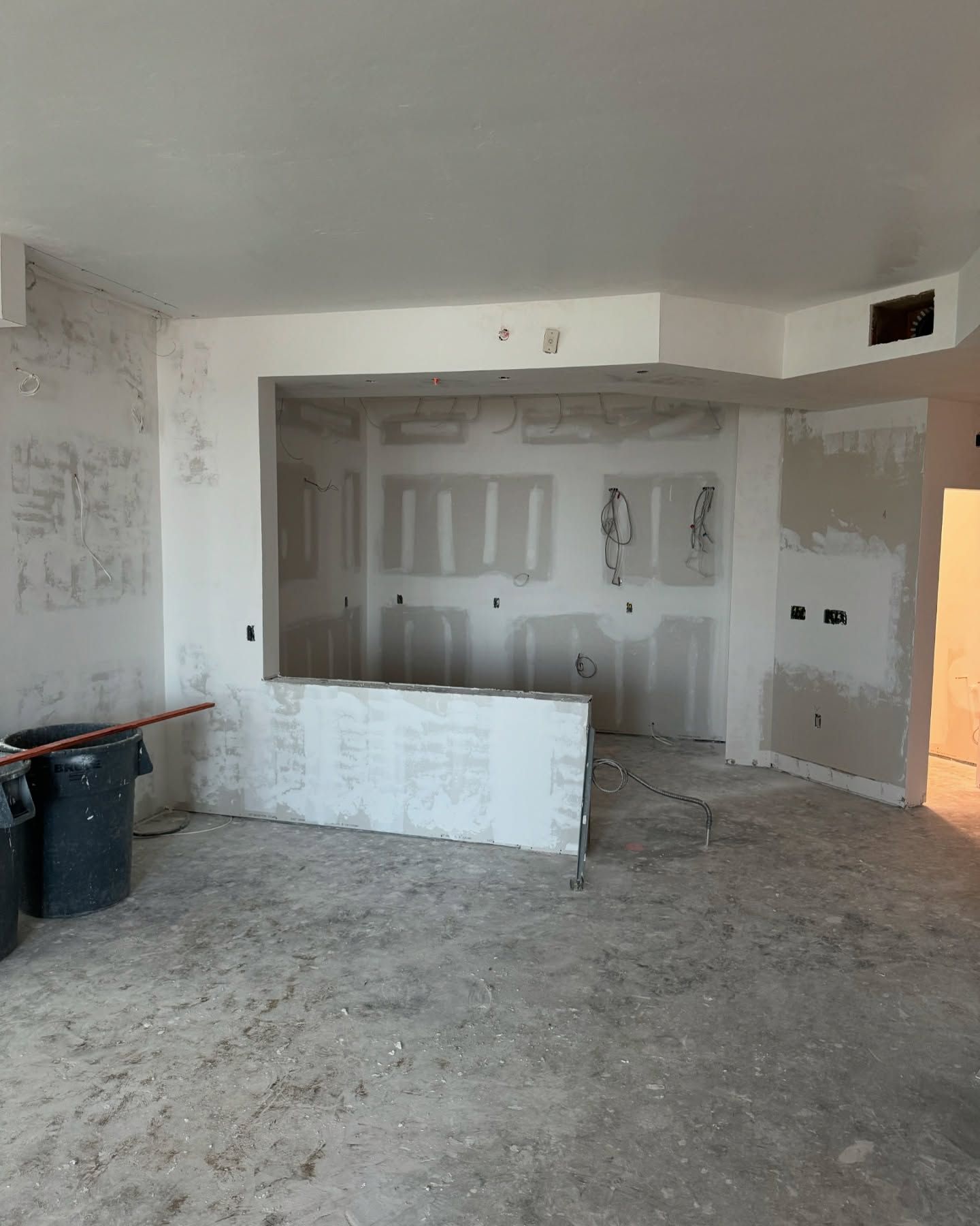 An empty room with a trash can in the middle of it