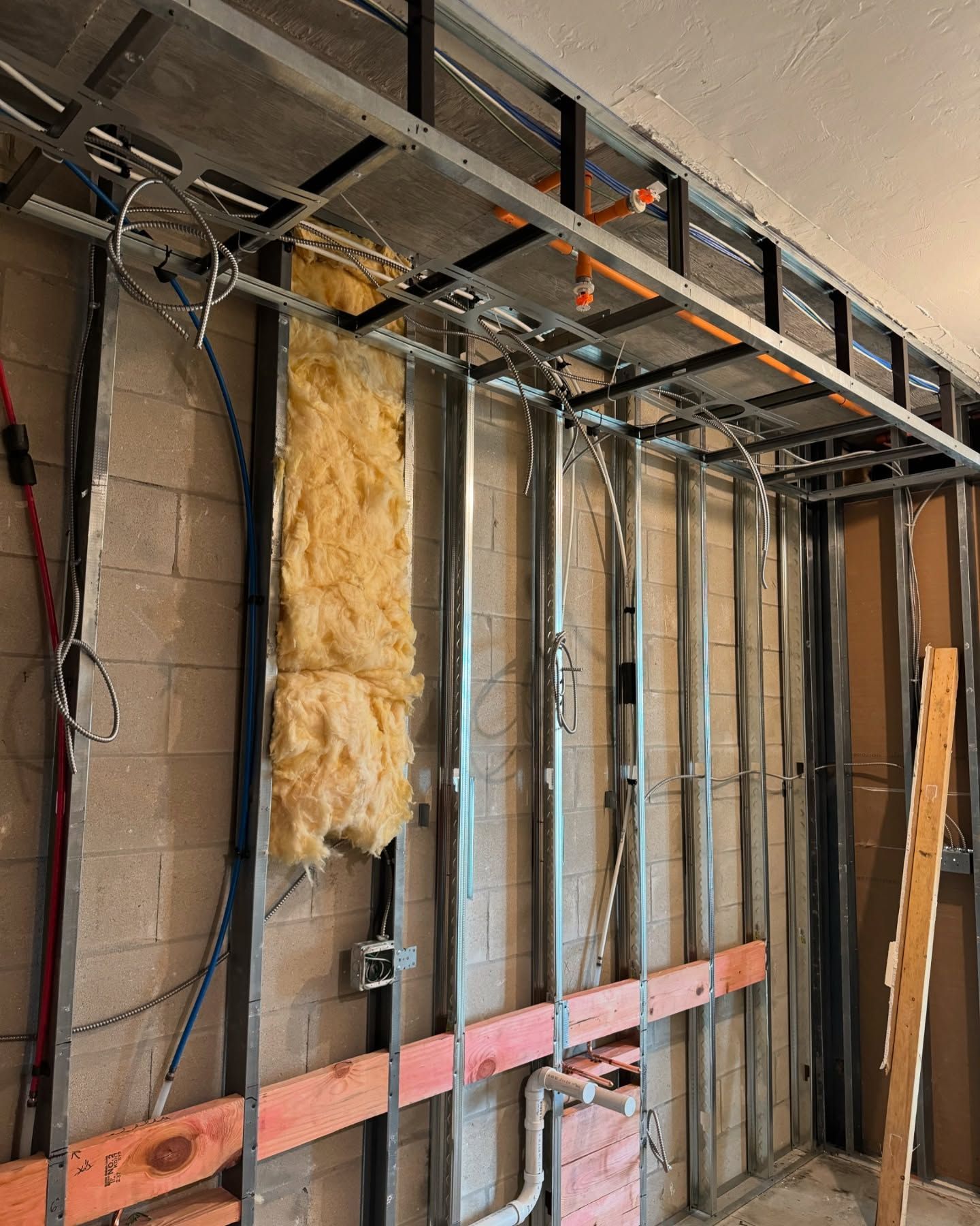 A room under construction with a lot of wires hanging from the ceiling.