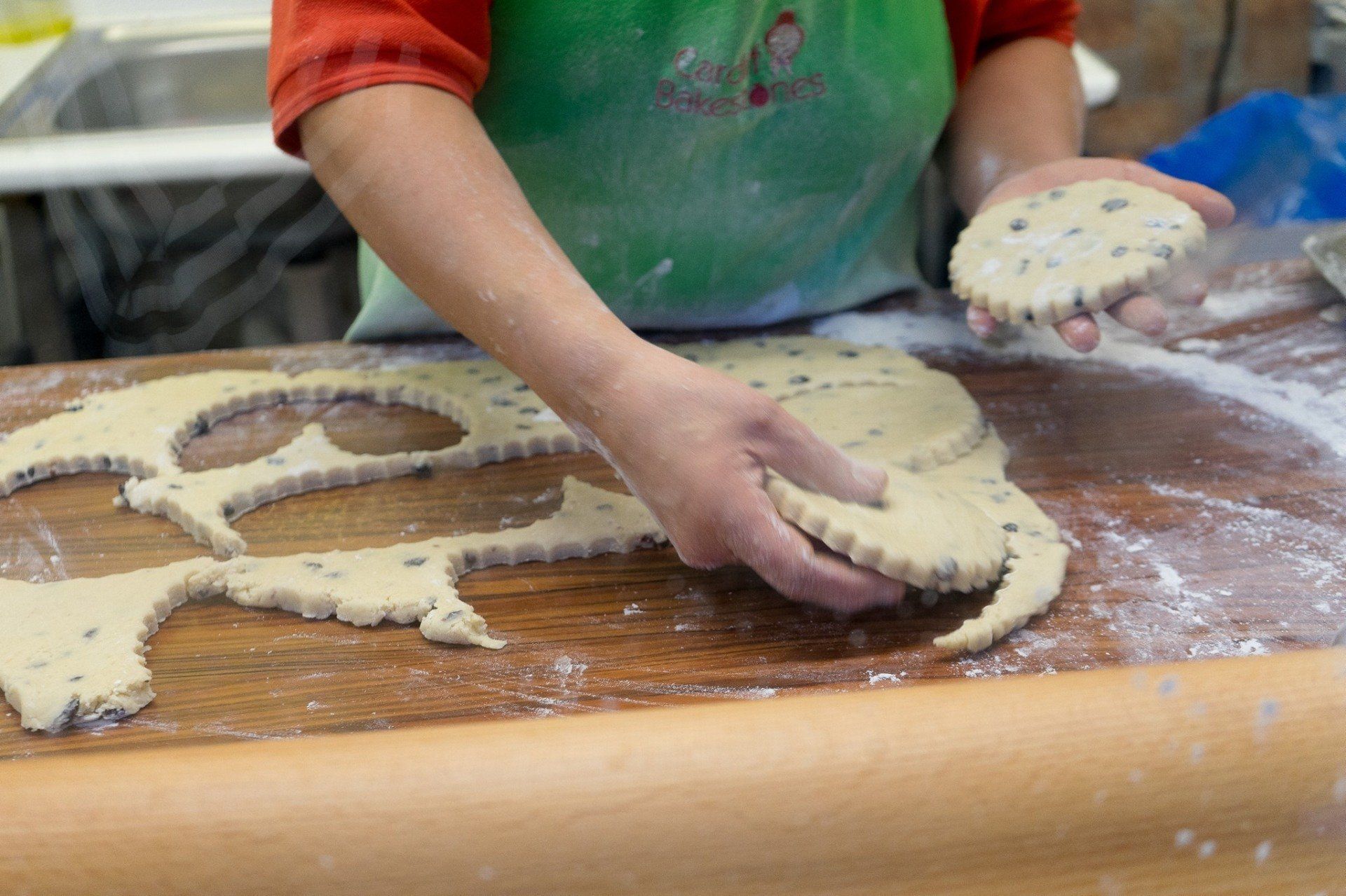 Bakestone Wales | A person is cutting dough into shapes on a wooden table.