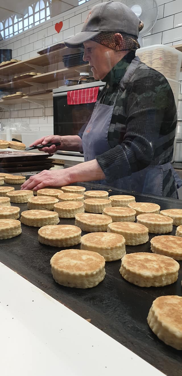 Bakestone Wales | A woman is baking bread on a conveyor belt in a bakery.