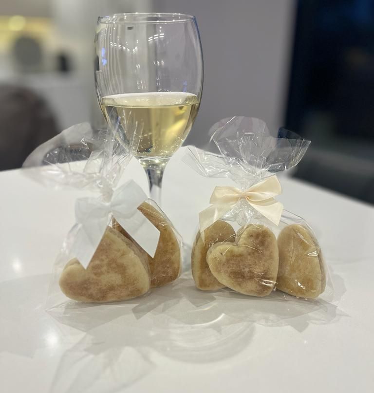 Bakestone Wales | Two heart shaped cookies are sitting on a table next to a glass of wine.