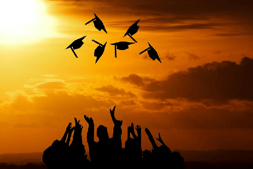 sunset with graduation students throwing caps