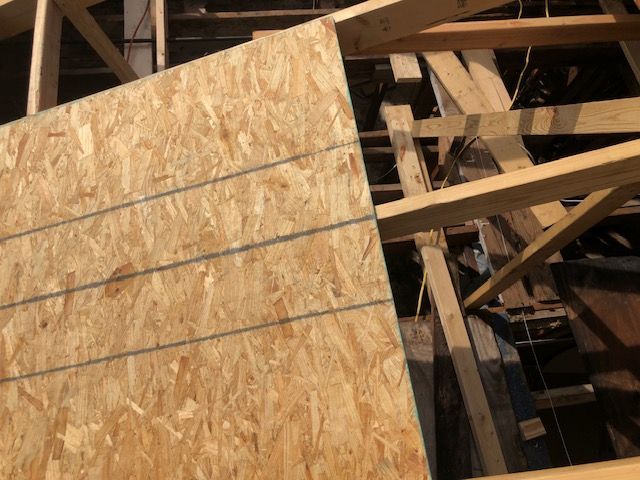 Stacked plywood sheets inside an unfinished wooden building frame.