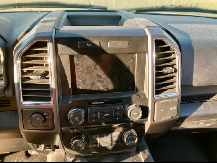 A close-up of a dirty truck dashboard with a radio on it