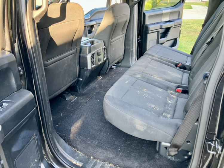 The rear seats of a black truck are dirty