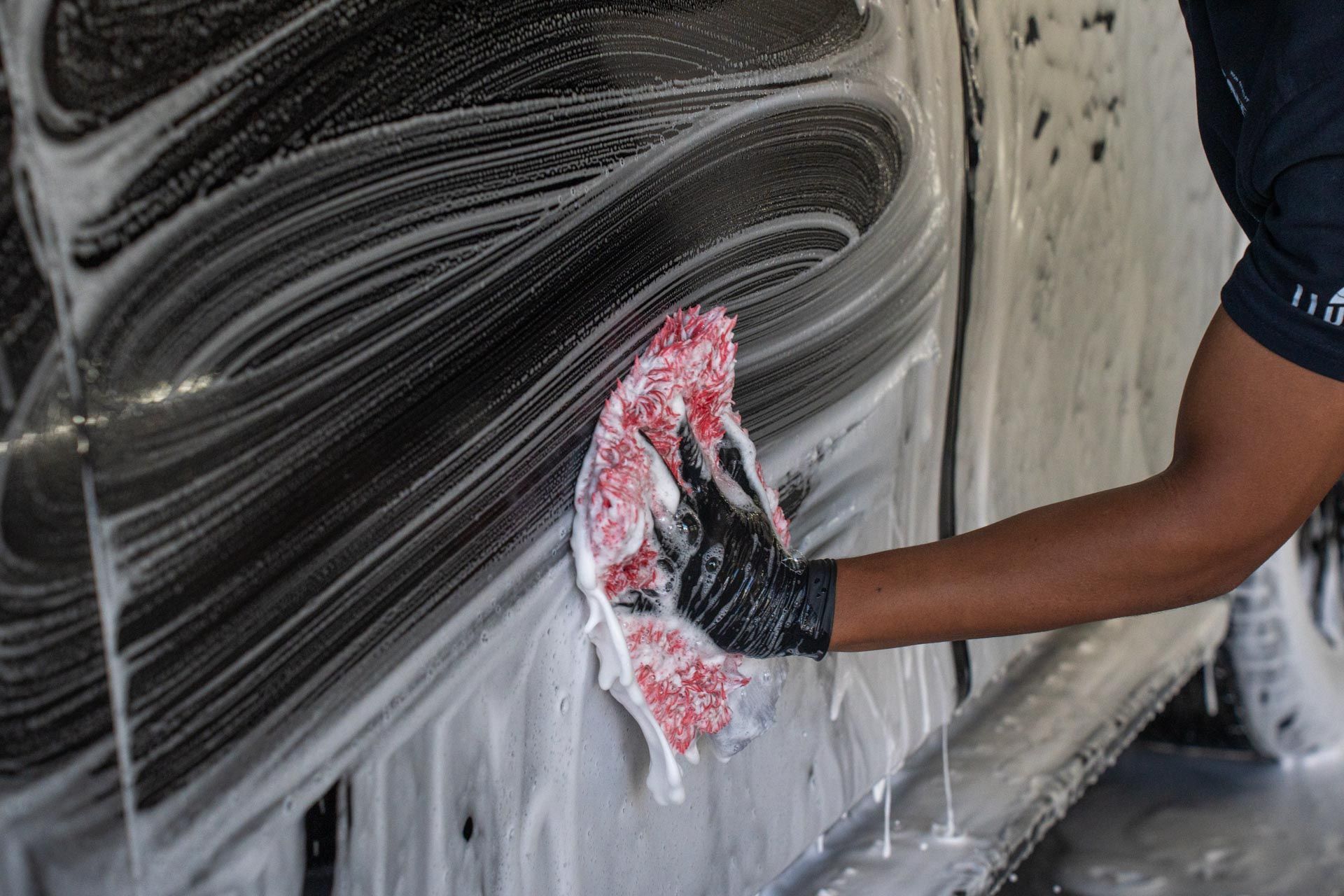 A person is cleaning a car with a towel and soap.