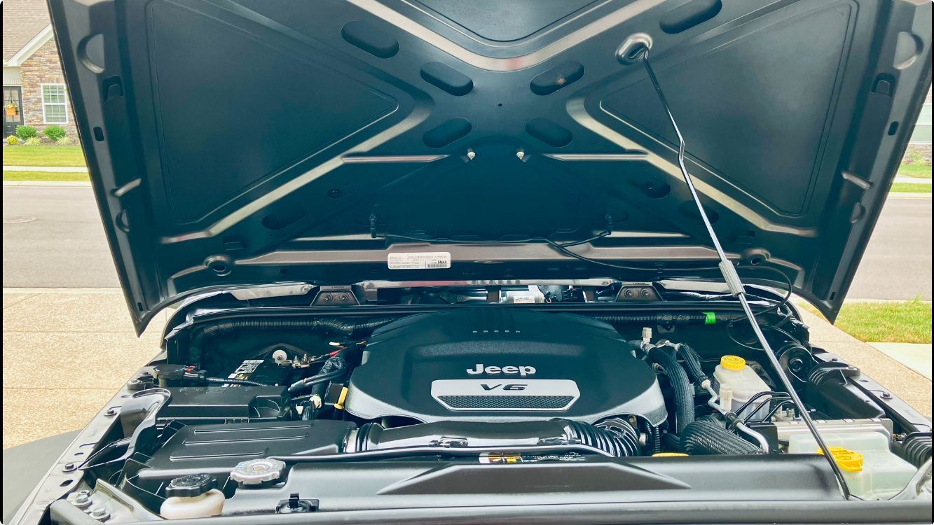 The hood of a jeep is open and shows the engine after deatiling