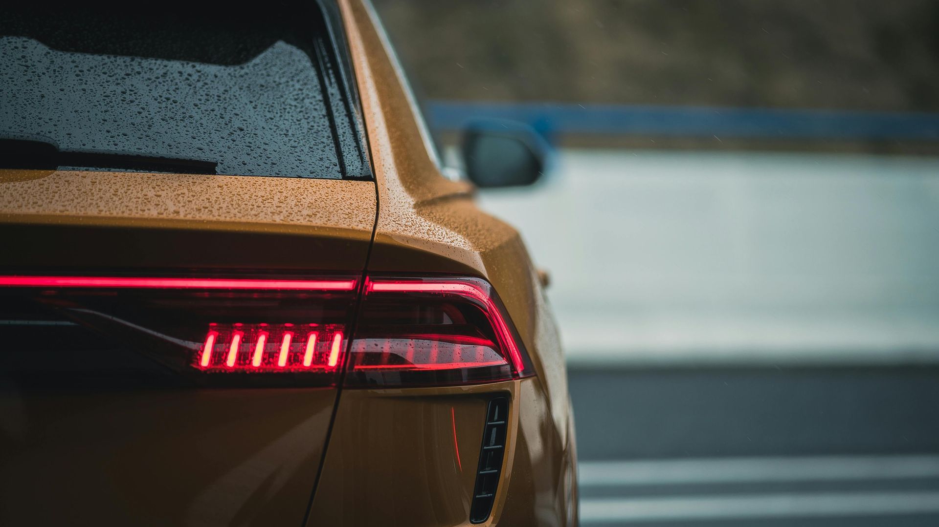 A close up of a car 's tail light on a wet road.