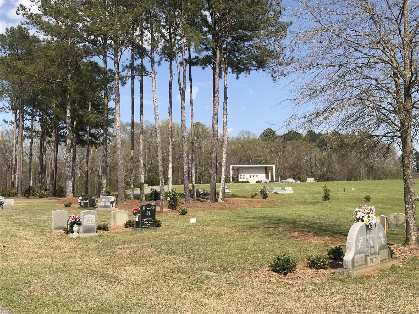 A cemetery filled with graves and trees on a sunny day.