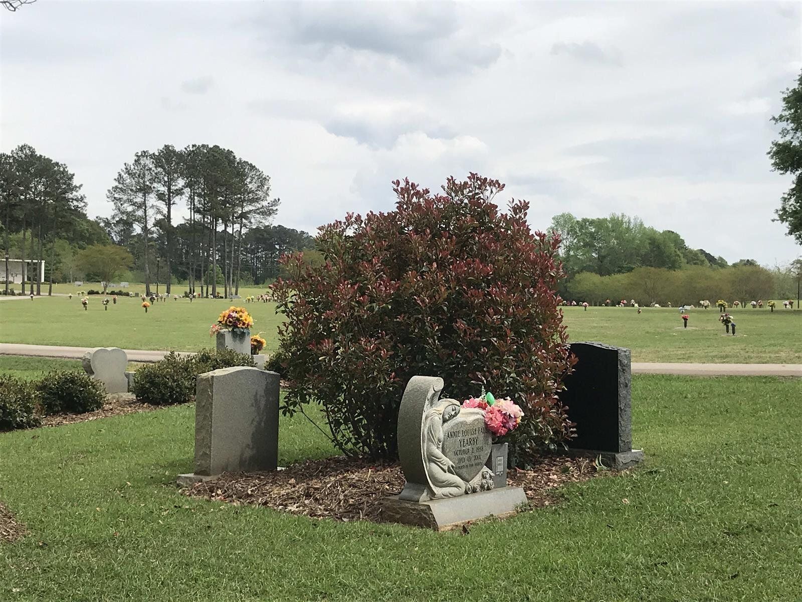 A cemetery with graves and flowers in the grass