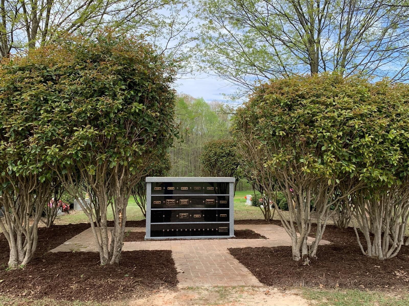 There is a memorial in the middle of a park surrounded by trees.